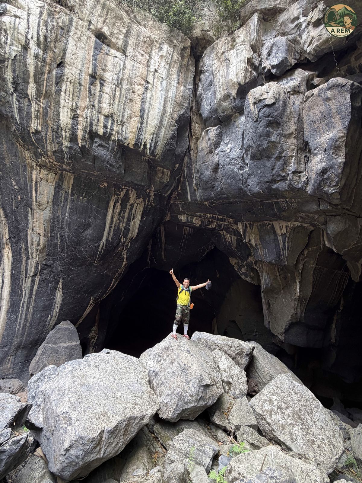 Traveler standing triumphant on a boulder pile inside the cave chamber