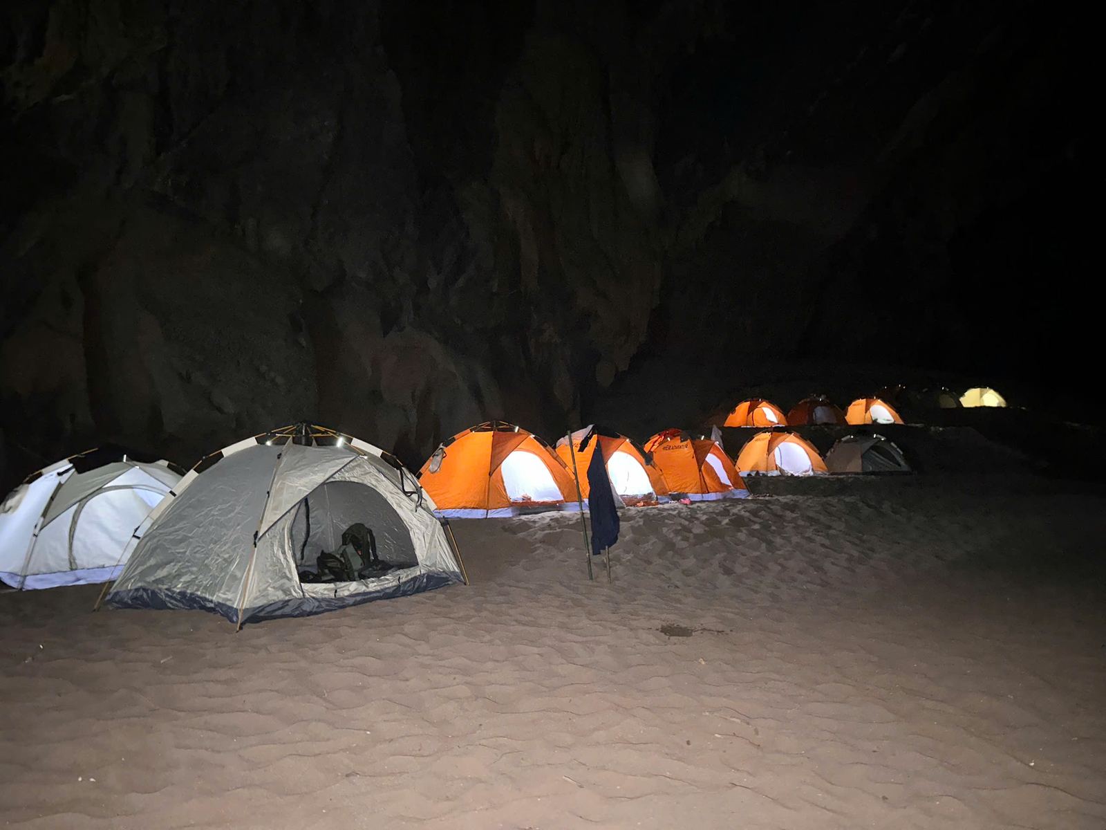 Camping tents lit up at night inside Kling Cave