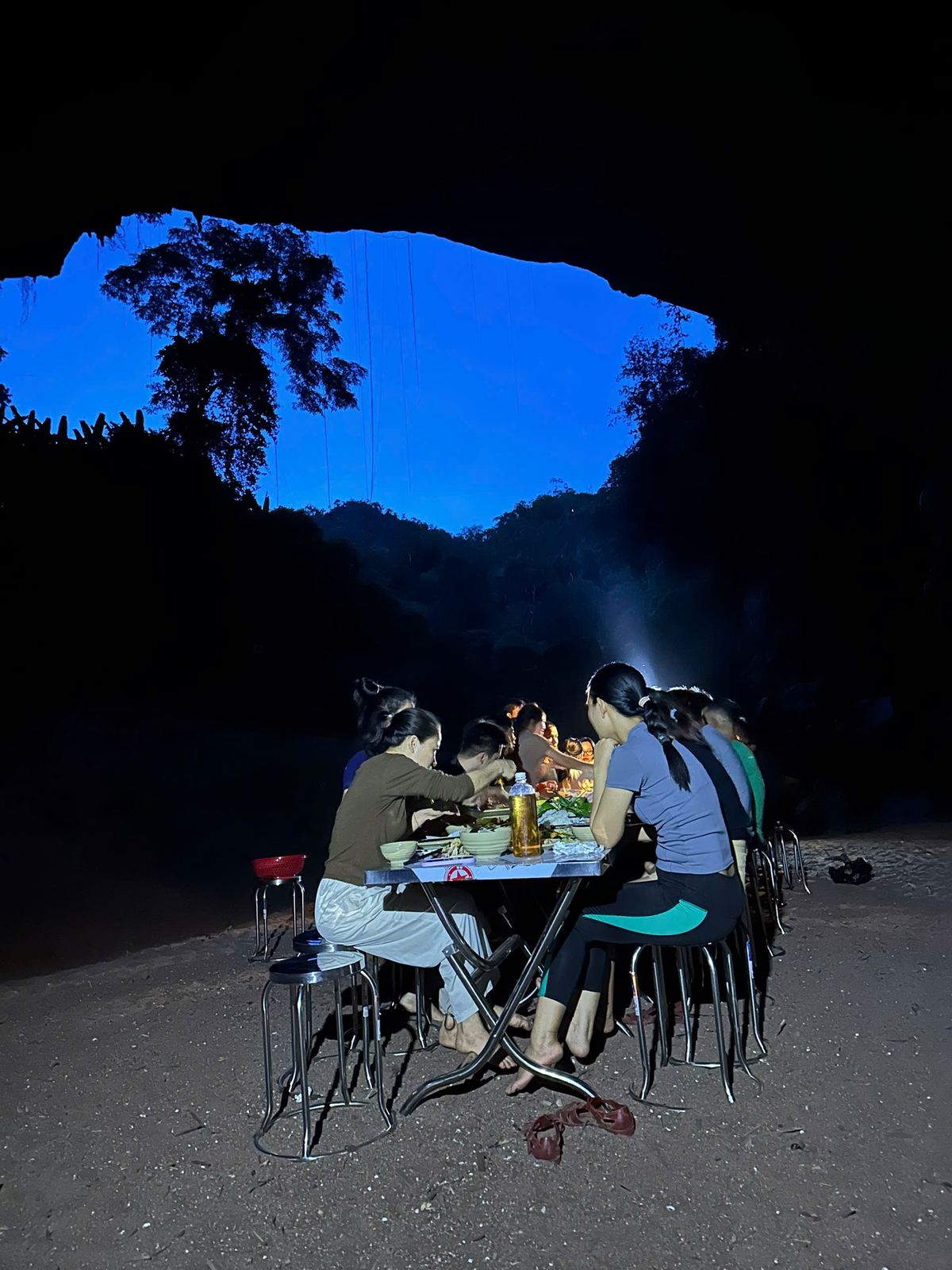 Group having dinner by lamplight inside the cave at night