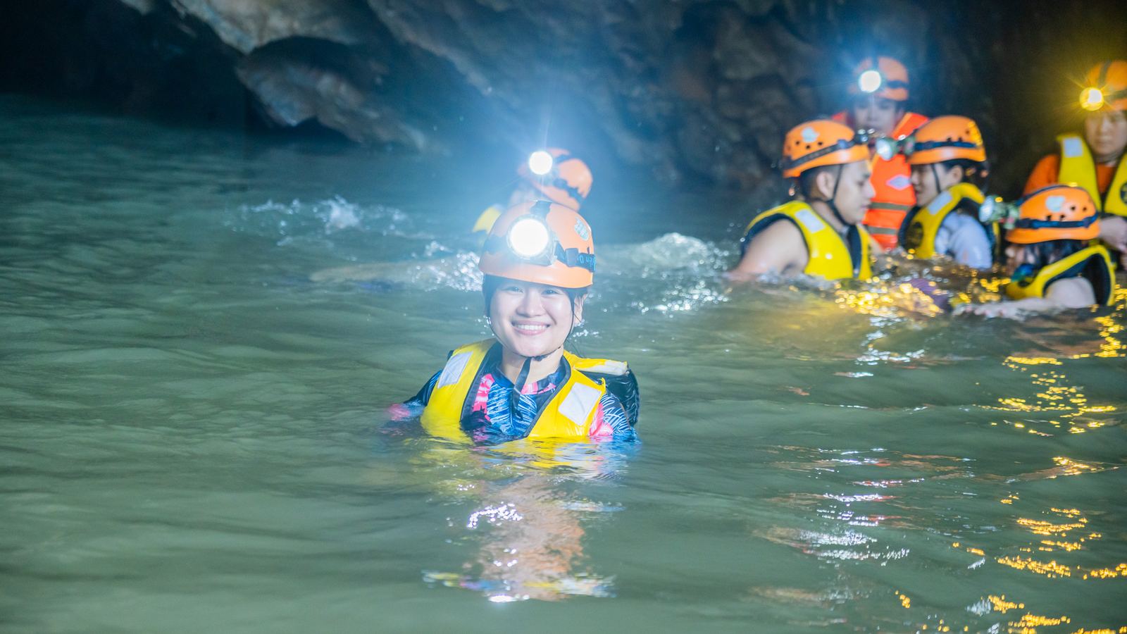 Group swimming with headlamps inside the cave