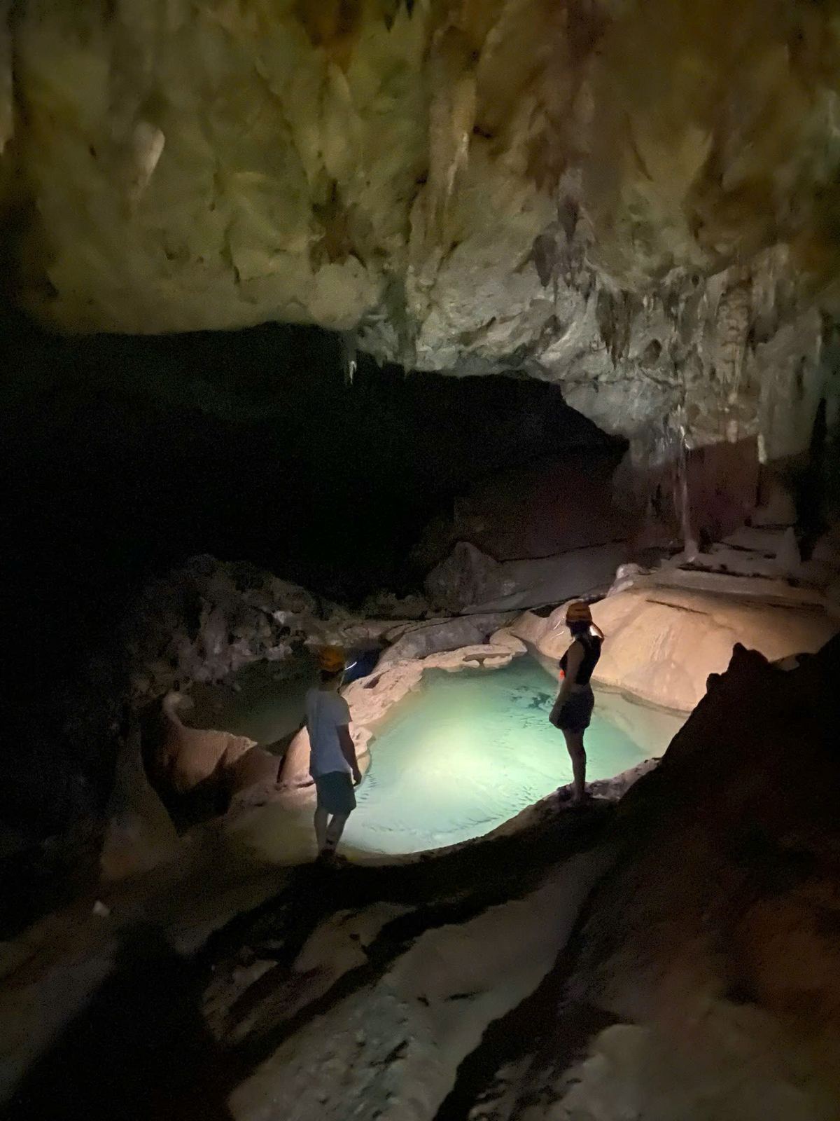 Person standing in an illuminated underground pool inside Phong Nha Cave