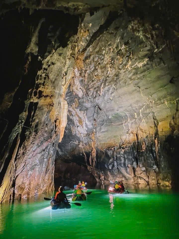 Travelers swimming in bright green underground lake water