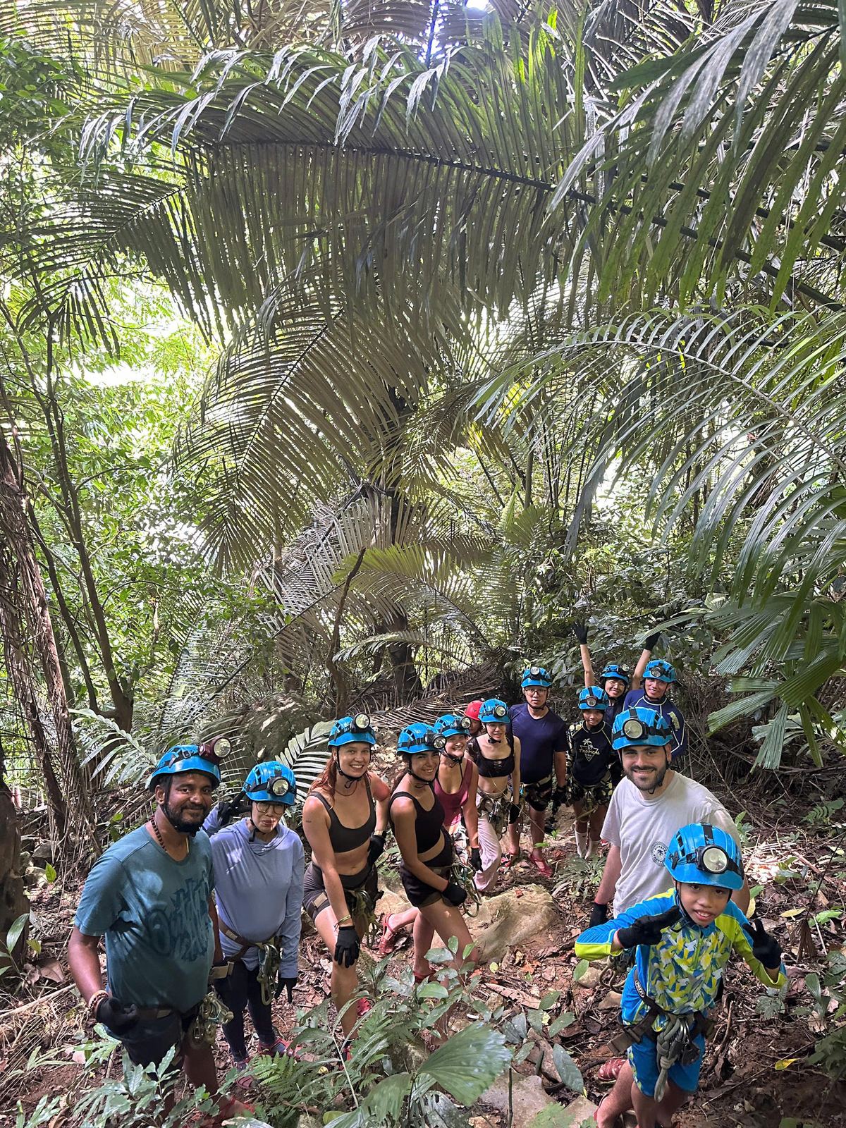 Group jungle trekking across a river to Ruc Mon cave